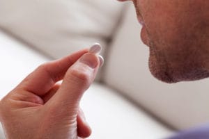 man about to put pill into his mouth during medication assisted treatment