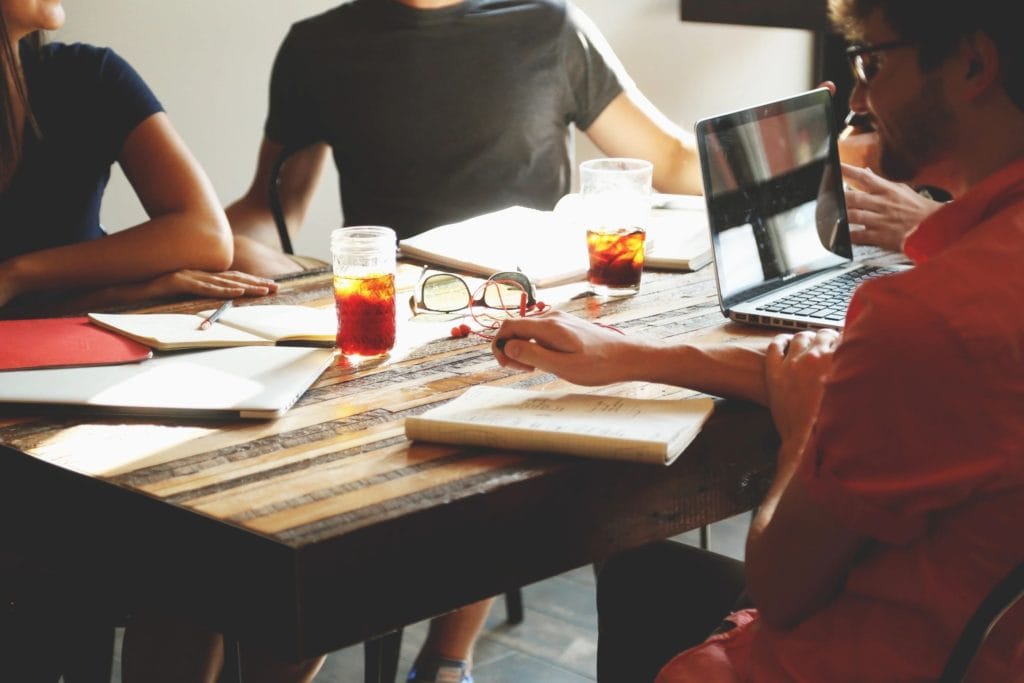 four people sit around a table with papers and a laptop working at boardprep recovery