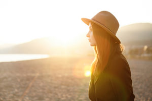 woman stands on the beach in the sun relaxing after her psychotherapy program