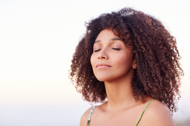 mixed race woman closes eyes outside after treating ptsd symptoms in women