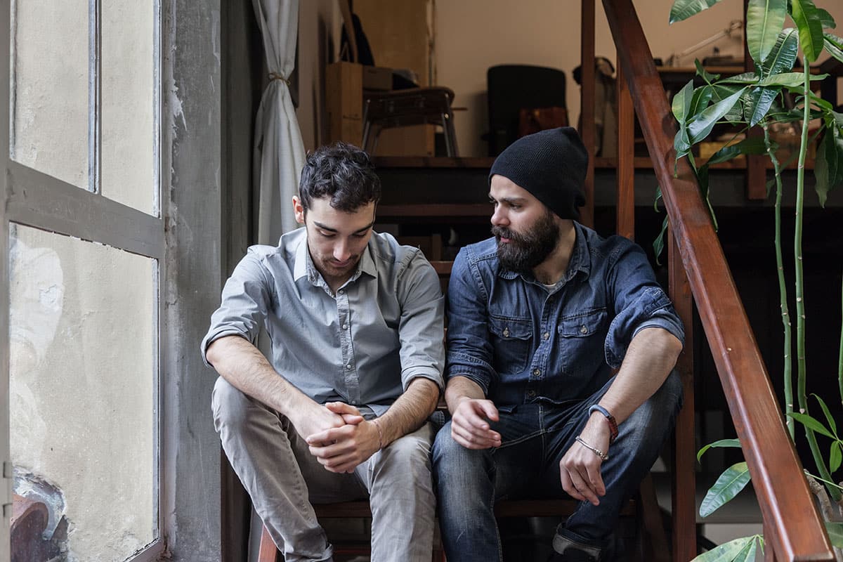 two men sitting on step discussing the value of sharing