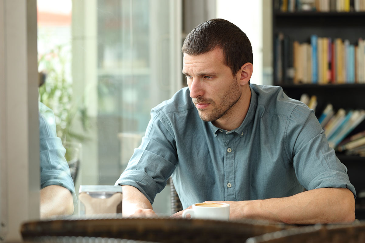 man staring out window in library during addiction recovery
