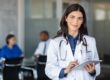 a doctor with a clipboard smiles as she considers physician health programs for addicted doctors