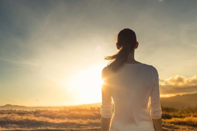 woman watches a sunset and prepares for recovery