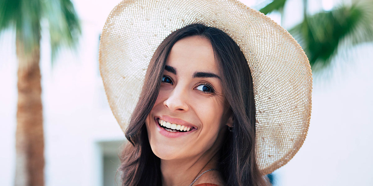 Self-Care as a Preventative Measure Against Relapse woman smiling over her shoulder in sun hat practicing self care