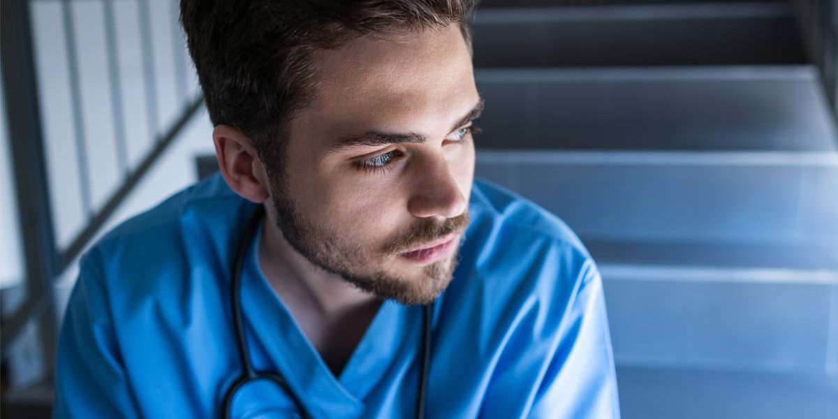 addiction-treatment-for-nurses nurse sitting in stairwell thinking about addiction treatment for nurses