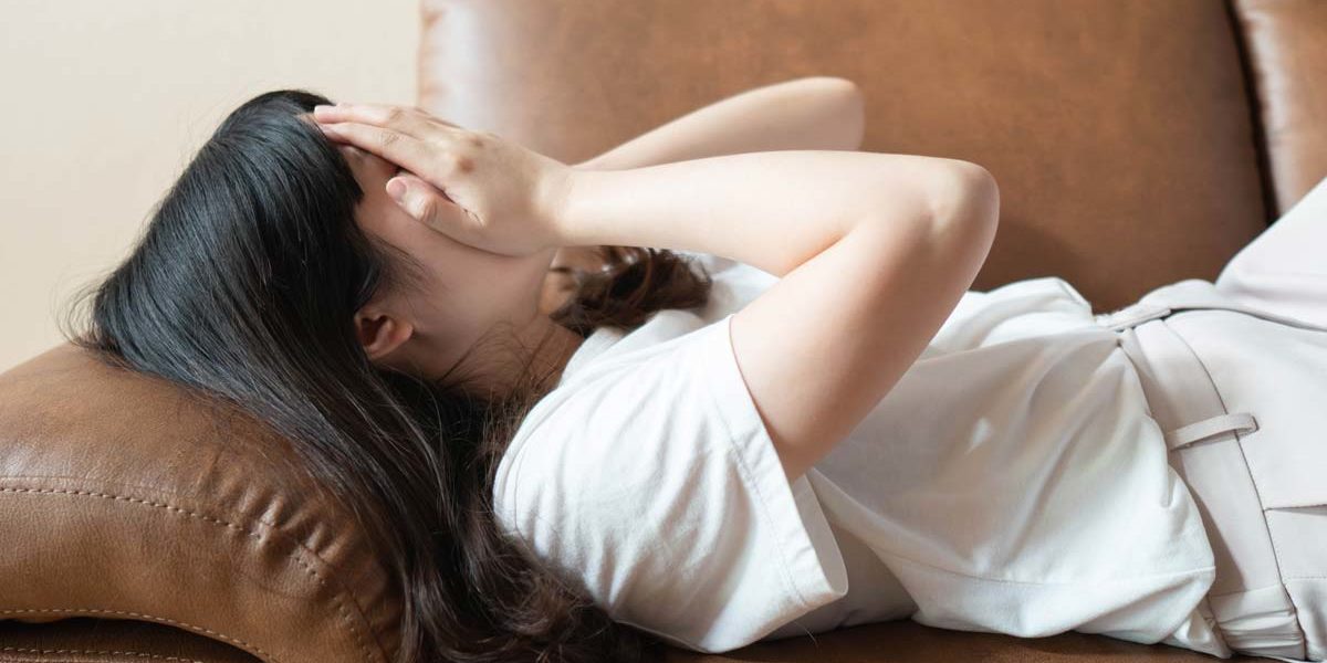 woman laying on couch covering face needing TMS Therapy for OCD