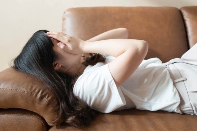 woman laying on couch covering face needing TMS Therapy for OCD