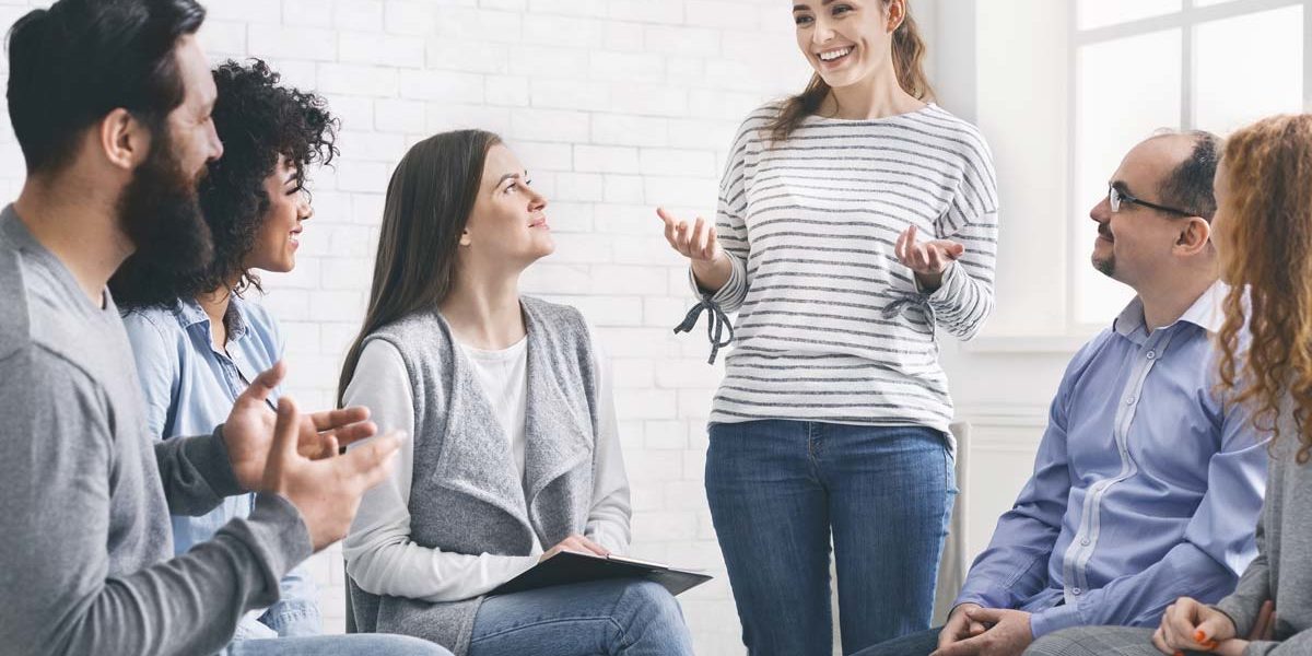 woman standing up talking to group about how a 12 step program helps recovery