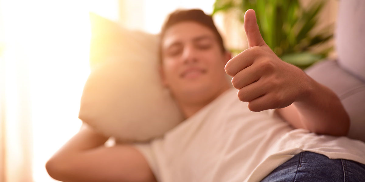 man laying on couch giving thumbs up for safety at rehab