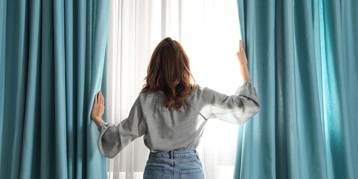 woman pulling back curtains to reveal addiction recovery