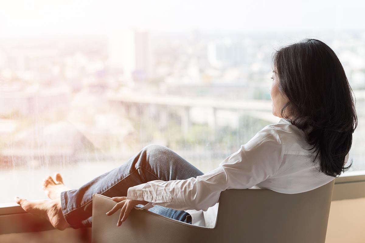 woman relaxing and looking out city window for self-care