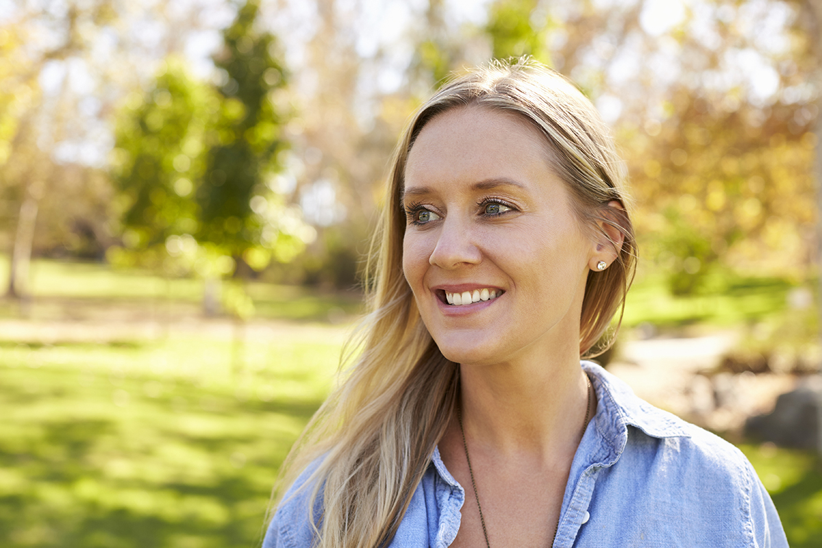 woman smiling on a walk in the park during daily recovery