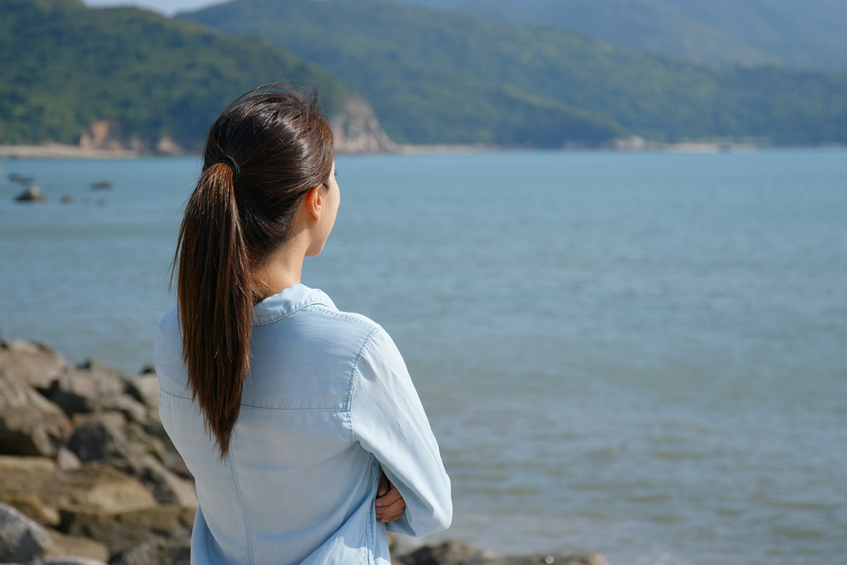 woman looking at the ocean thinking how addiction does not discriminate