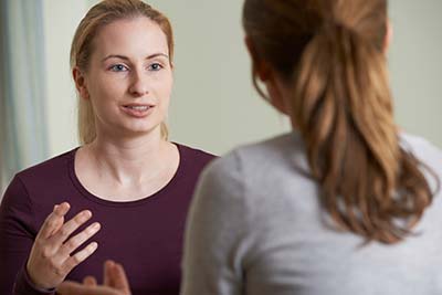 woman talking with therapist at rehab about cognitive behavioral therapy