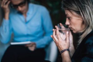 a woman sips water while receiving addiction therapy services in tampa