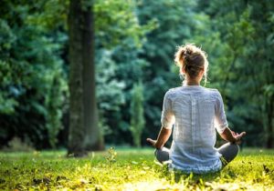 a woman meditates in nature as part of her holistic therapy program for addiction treatment 